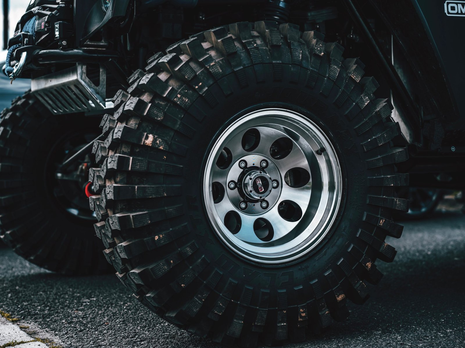 Detailed shot of a rugged off-road vehicle tire on asphalt.